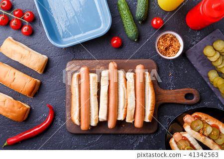 Picture on top of two hotdogs on cutting board on table with sausages 41342563