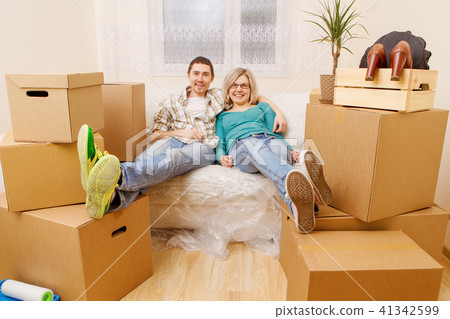 Photo of couple sitting on couch among cardboard boxes 41342599