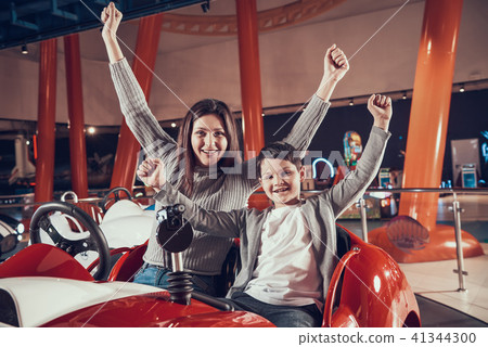 Happy smiling mother and son sitting on toy car Happy smiling mother and son sitting on toy car 41344300