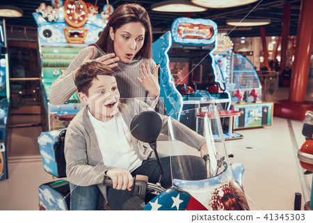 Mom and son in amusement park on toy motorcycle Mom and son in amusement park on toy motorcycle 41345303