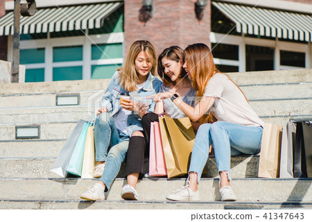Asian woman use smartphone while shopping in city. Asian woman use smartphone while shopping in city. 41347643