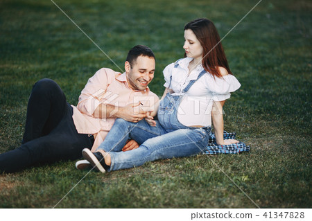 Pregnant couple sitting in the park chatting Pregnant couple sitting in the park chatting 41347828