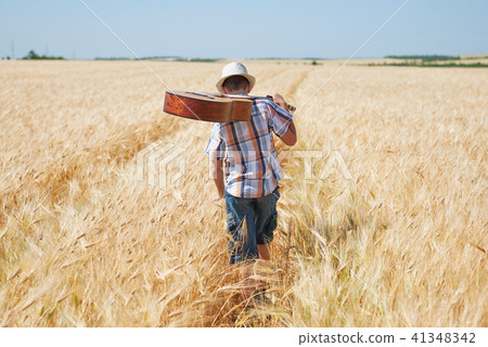 child boy with guitar is in the yellow wheat field 41348342