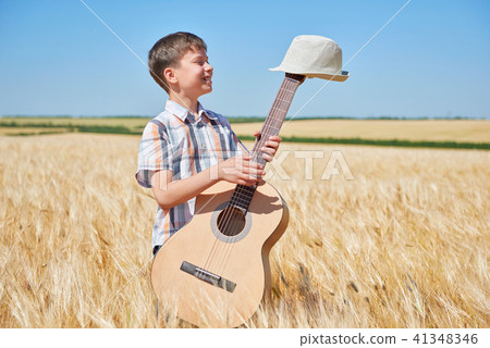 child boy with guitar is in the yellow wheat field 41348346