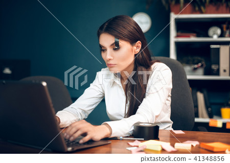 Woman trying to keep her eyes open while working. 41348856