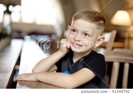 little boy 4-5 years old sitting at the wooden table in cafe little boy 4-5 years old sitting at the wooden table in cafe 41349792
