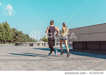 Pretty sporty woman and man jogging at city 41350144