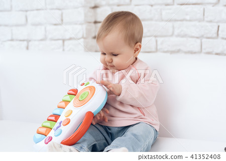 Smiling newborn baby on sofa playing toy. 41352408