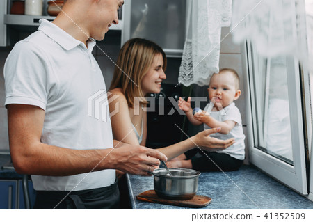 Parents feeding baby daughter at home kitchen 41352509