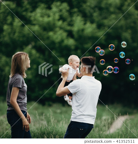 Family playing outdoors, blowing soap bubbles. Family playing outdoors, blowing soap bubbles. 41352511