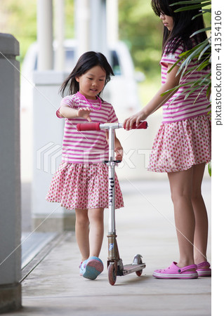 Children sister playing the scooter 41354106