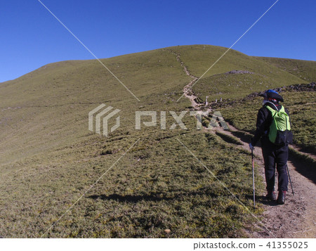 一名男性登山客走在高山上的小徑上, 天氣非常好, 可以看到清澈的藍天, 走起來非常舒適, 心情愉悅 一名男性登山客走在高山上的小徑上, 天氣非常好, 可以看到清澈的藍天, 走起來非常舒適, 心情愉悅 41355025