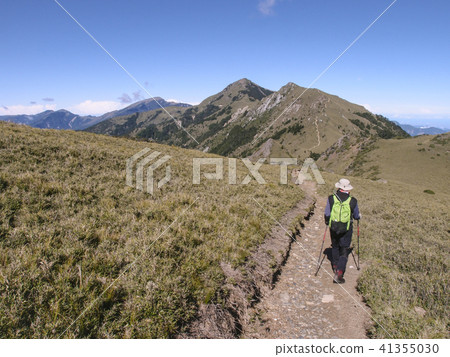 一名男性登山客走在高山上的小徑上, 天氣非常好, 可以看到清澈的藍天, 走起來非常舒適, 心情愉悅 41355030
