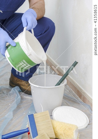 Painter paints the wall with the tint of white. 41358615
