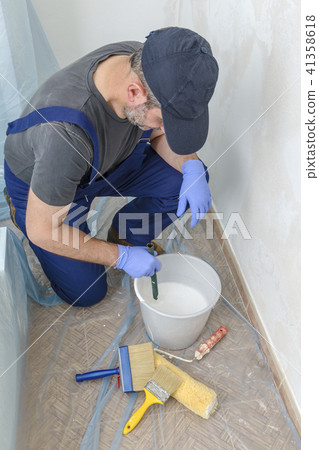 Painter paints the wall with the tint of white. Painter paints the wall with the tint of white. 41358618