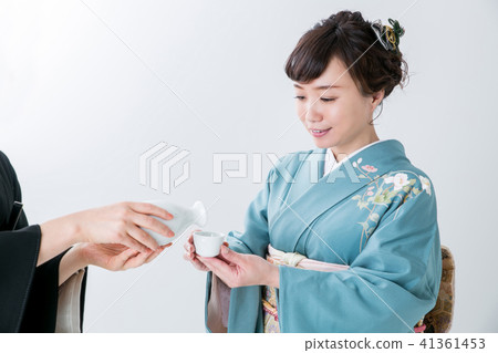 A woman in kimonos poured sake A woman in kimonos poured sake 41361453