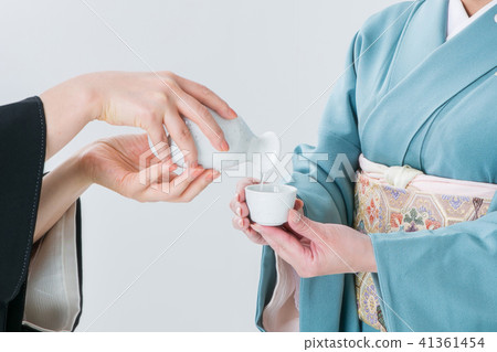 A woman in kimonos poured sake A woman in kimonos poured sake 41361454