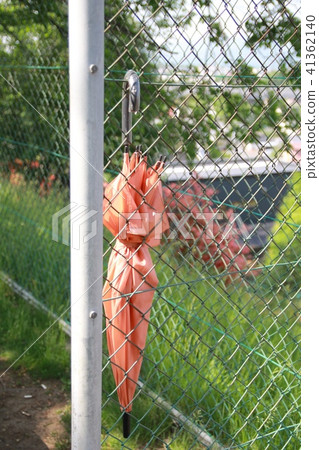 A lost umbrella hanging on a fence in a park A lost umbrella hanging on a fence in a park 41362140
