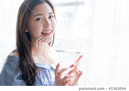 A woman standing at a window 41363084