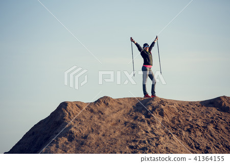 Full-length photo of woman growing tourist with backpack and walking sticks with her hands up on 41364155