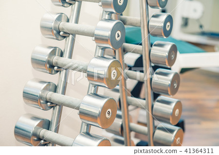 Rows of metal dumbbells on stand in sport gym Rows of metal dumbbells on stand in sport gym 41364311