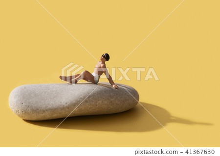 miniature man sunbathing on a rock 41367630