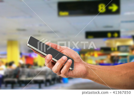 Hand holding mobile phone in departure hall 41367850