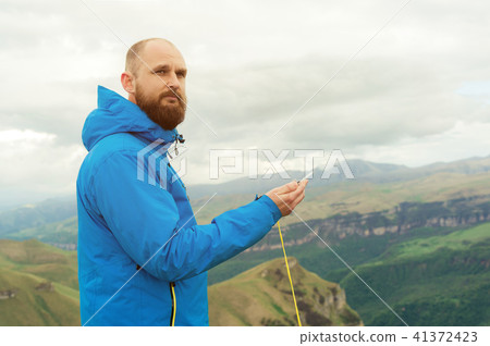 Hipster man in a blue jacket using a compass on the background in the background of the Caucasian Hipster man in a blue jacket using a compass on the background in the background of the Caucasian 41372423