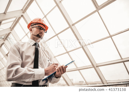 Young serious architect in helmet in office Young serious architect in helmet in office 41373138