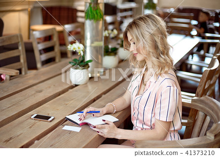 young freelancer woman writting plans in notebook at the table 41373210