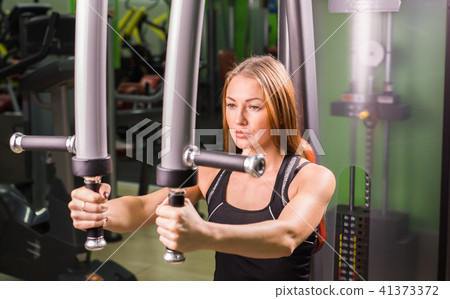 Caucasian fitness woman is working out on butterfly machine in gym Caucasian fitness woman is working out on butterfly machine in gym 41373372