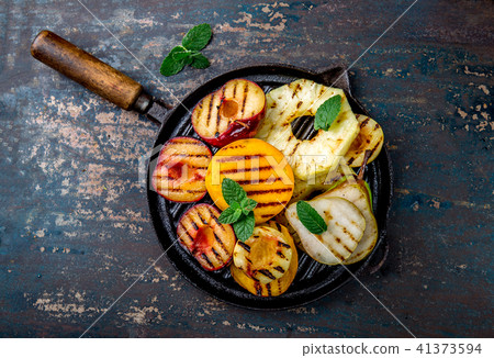 GRILLED FRUITS. Grill fruits - pineapple, peaches, plums, avocado, pear on black cast iron grill pan GRILLED FRUITS. Grill fruits - pineapple, peaches, plums, avocado, pear on black cast iron grill pan 41373594