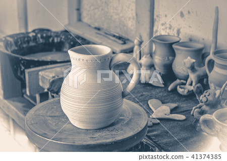 Old vintage photo. Clay jug on a potter's wheel close-up. Old vintage style. 41374385