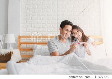 Happy Asian couple looking positive pregnancy test Happy Asian couple looking positive pregnancy test 41377650