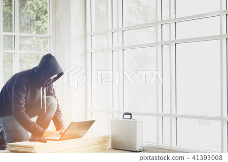 Hacker holding gun working on his computer Hacker holding gun working on his computer 41393008