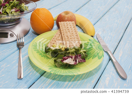 Delicious salad of green herbs on a plate, kitchen scales. The concept of proper nutrition. Diet Delicious salad of green herbs on a plate, kitchen scales. The concept of proper nutrition. Diet 41394739