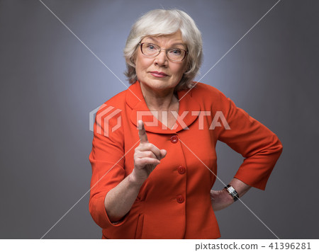 Senior lady points finger up 41396281