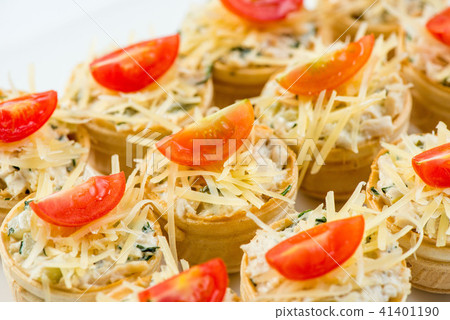 Three baguette slices with liver and apple pate and a thin tomato slice on top. Shallow DOF 41401190