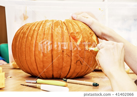 Women's hands who cuts jack-o-lantern with knife Women's hands who cuts jack-o-lantern with knife 41402066