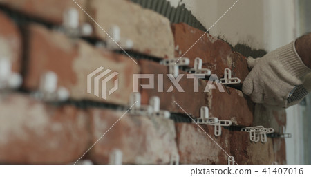 closeup worker applying brick cuts tile to the wall closeup worker applying brick cuts tile to the wall 41407016