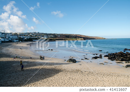 岩石和小山包圍的一個淺沙子海灘人們使用在海岸和沙盒人在英國郊區 41411607