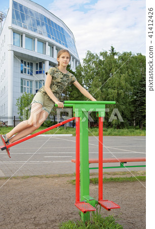 Teen girl trains on a swinging simulator outdoors 41412426
