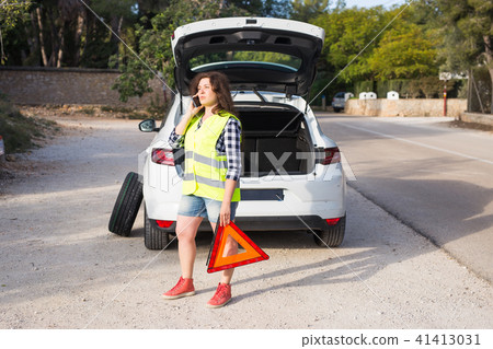 Broken down car with warning triangle. Woman standing alongside her broken down car on the road and 41413031