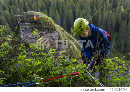 girl climber begin descent from the cliff.. girl climber begin descent from the cliff.. 41413604