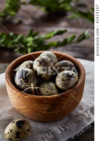 Bowl with eggs quail, eggs on a homespun napkin, boxwood on wooden background, close-up, selective Bowl with eggs quail, eggs on a homespun napkin, boxwood on wooden background, close-up, selective 41414167