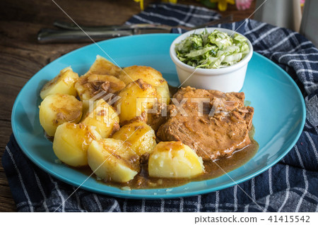 Braised meat in sauce served with boiled potatoes. 41415542