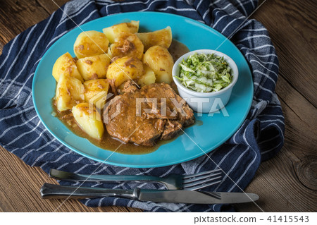 Braised meat in sauce served with boiled potatoes. 41415543