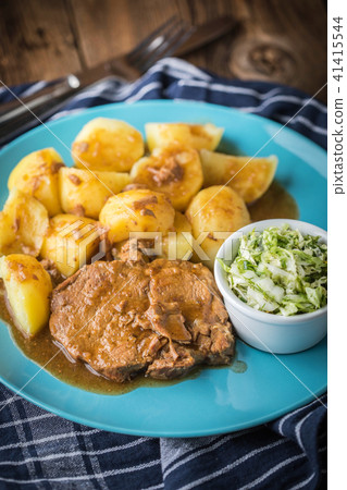 Braised meat in sauce served with boiled potatoes. 41415544