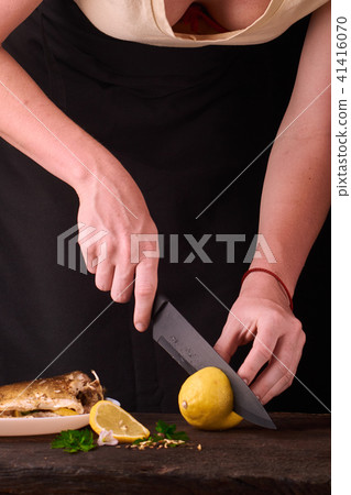 woman cutting lemon for baked fish woman cutting lemon for baked fish 41416070