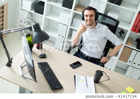 A young man in headphones sits at a computer desk. A young man in headphones sits at a computer desk. 41417134